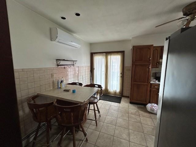 735 Park Ave, Johnstown, PA 15902 - dining room featuring a wall mounted AC, ceiling fan, light tile patterned floors, tile walls, and a wainscoted wall