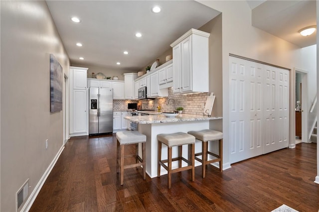 139 Canter Ln, West Deer, PA 15044 - kitchen with stainless steel appliances, a peninsula, dark wood-type flooring, tasteful backsplash, and white cabinetry