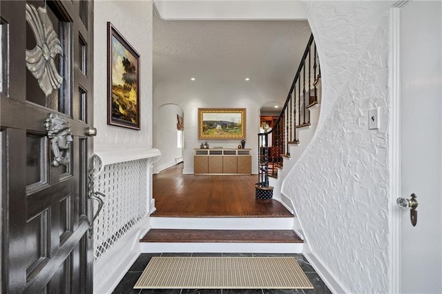 6820 Edgerton, Point Breeze, PA 15208 - entryway with stairs, arched walkways, tile patterned floors, a textured wall, and a baseboard radiator