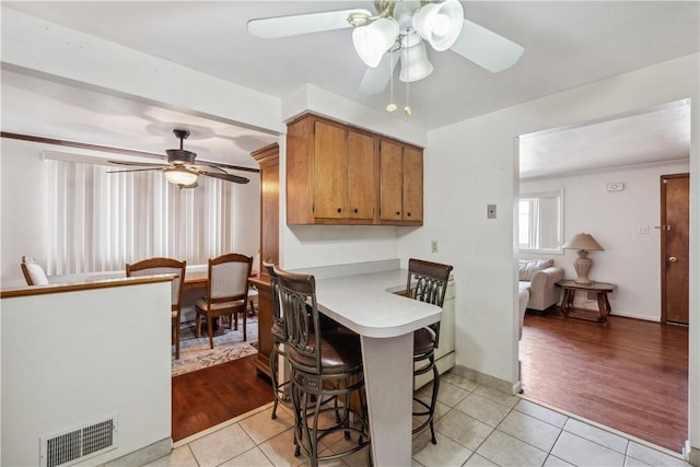 638 Friday Rd, Shaler, PA 15209 - kitchen with a ceiling fan, light tile patterned flooring, brown cabinetry, a kitchen breakfast bar, and light countertops