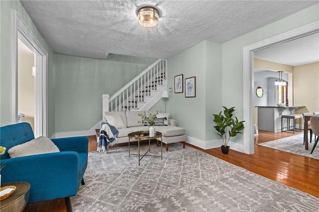 907 Greenfield Ave, Greenfield, PA 15217 - living room featuring wood finished floors, baseboards, stairs, and a textured ceiling