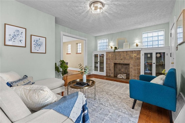 907 Greenfield Ave, Greenfield, PA 15217 - living room with wood finished floors, healthy amount of natural light, a textured ceiling, a fireplace, and baseboards