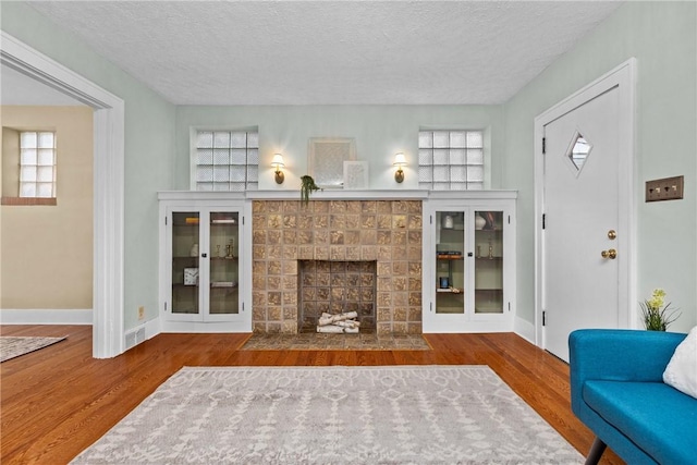 907 Greenfield Ave, Greenfield, PA 15217 - living area featuring a textured ceiling, wood finished floors, baseboards, a brick fireplace, and plenty of natural light
