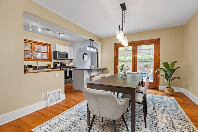 907 Greenfield Ave, Greenfield, PA 15217 - dining room with light wood-style flooring, baseboards, a chandelier, and arched walkways