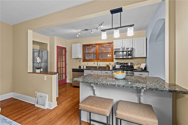 907 Greenfield Ave, Greenfield, PA 15217 - kitchen with stainless steel appliances, a breakfast bar area, light wood-style floors, and baseboards