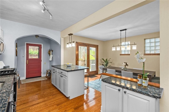907 Greenfield Ave, Greenfield, PA 15217 - kitchen with stainless steel range with gas stovetop, white cabinetry, light wood-style flooring, arched walkways, and healthy amount of natural light