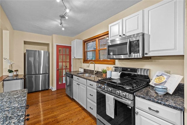 907 Greenfield Ave, Greenfield, PA 15217 - kitchen featuring appliances with stainless steel finishes, a sink, wood finished floors, white cabinets, and dark stone counters