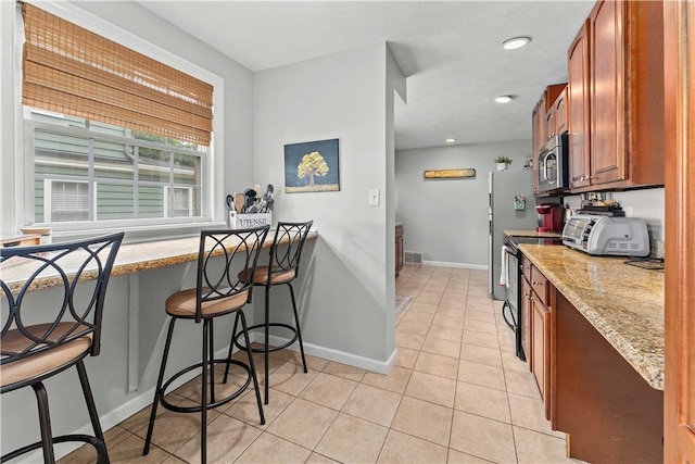55 Evergreen Ter, Uniontown, PA 15401 - kitchen featuring appliances with stainless steel finishes, light tile patterned floors, light stone counters, baseboards, and a breakfast bar area