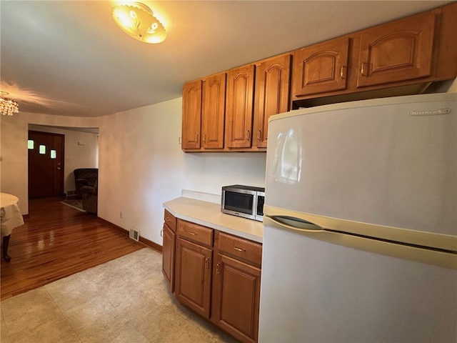1132 Onondago St, Squirrel Hill, PA 15218 - kitchen featuring freestanding refrigerator, stainless steel microwave, brown cabinetry, light countertops, and baseboards