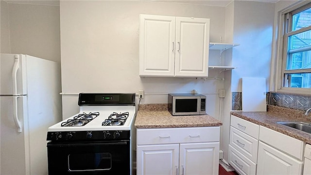 144 N Dithridge St Unit 703, Oakland, PA 15213 - kitchen featuring gas range oven, stainless steel microwave, freestanding refrigerator, a sink, and white cabinets