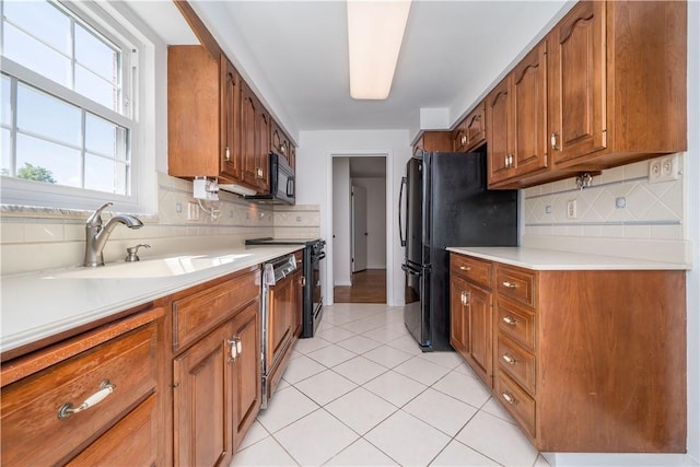 2443 Rose Garden Rd, Banksville/Westwood, PA 15220 - kitchen featuring brown cabinetry, tasteful backsplash, light countertops, and black appliances