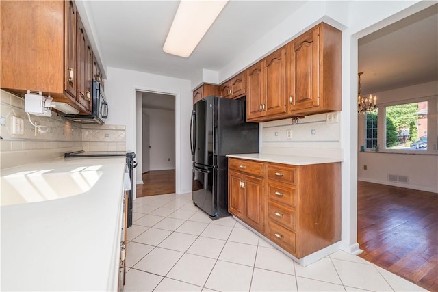 2443 Rose Garden Rd, Banksville/Westwood, PA 15220 - kitchen with freestanding refrigerator, brown cabinets, light countertops, a chandelier, and decorative backsplash