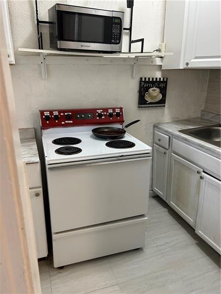 1015 Gerritt St, Homewood-Brushton, PA 15208 - kitchen featuring white range with electric cooktop, stainless steel microwave, light countertops, and a sink