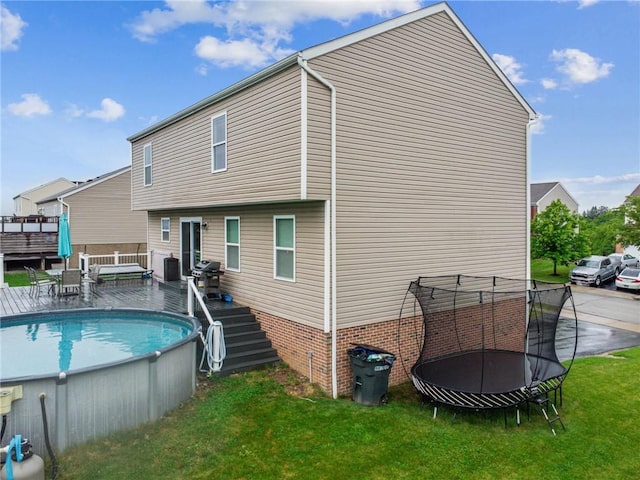 11572 Salerno Dr, North Huntingdon, PA 15642 - rear view of property featuring a wooden deck, an outdoor pool, a yard, and a trampoline