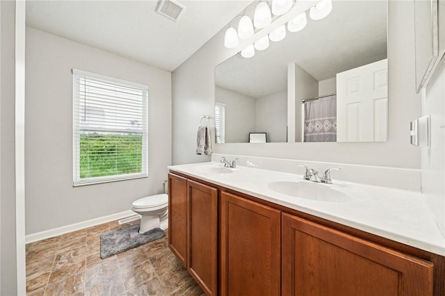 11572 Salerno Dr, North Huntingdon, PA 15642 - bathroom with double vanity, toilet, baseboards, and stone finish floors
