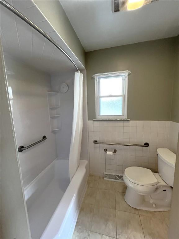 122 E Elizabeth St, New Castle/2Nd, PA 16105 - bathroom featuring toilet, tile walls, tile patterned flooring, wainscoting, and shower / tub combo