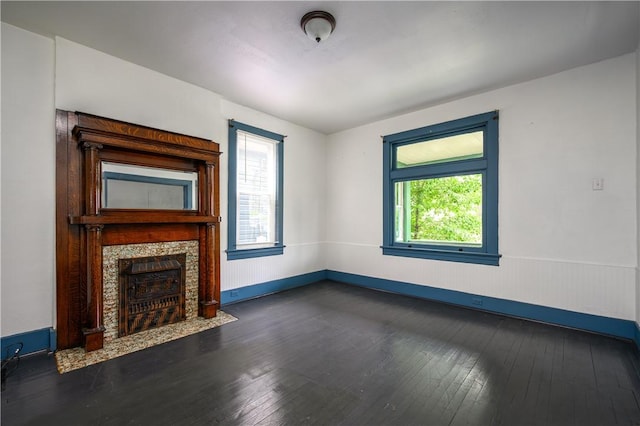 920 Roup Ave, Brackenridge, PA 15014 - unfurnished living room featuring dark wood-type flooring, a tiled fireplace, a wainscoted wall, and baseboards