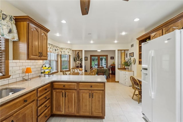 108 Covington Dr, Center Twp, PA 16001 - kitchen with white fridge with ice dispenser, a peninsula, light stone countertops, brown cabinets, and tasteful backsplash