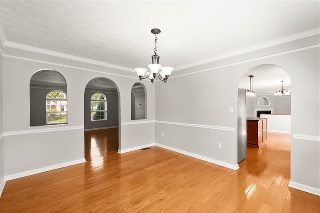821 Kingston Dr, South Fayette, PA 15057 - empty room with a chandelier, light wood-style flooring, arched walkways, ornamental molding, and baseboards