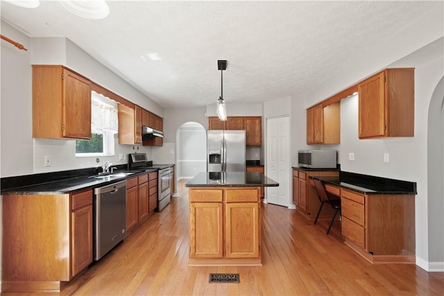 821 Kingston Dr, South Fayette, PA 15057 - kitchen featuring appliances with stainless steel finishes, arched walkways, dark countertops, and light wood finished floors