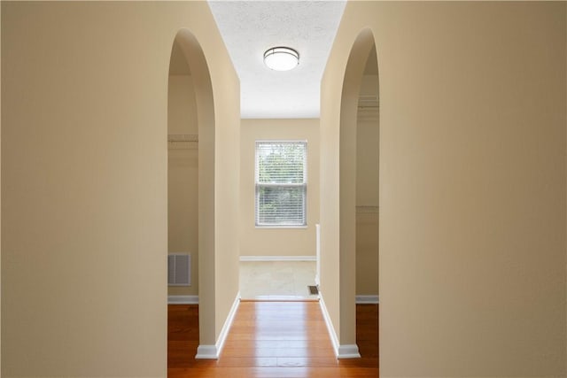 821 Kingston Dr, South Fayette, PA 15057 - corridor with wood finished floors, baseboards, a textured ceiling, and arched walkways