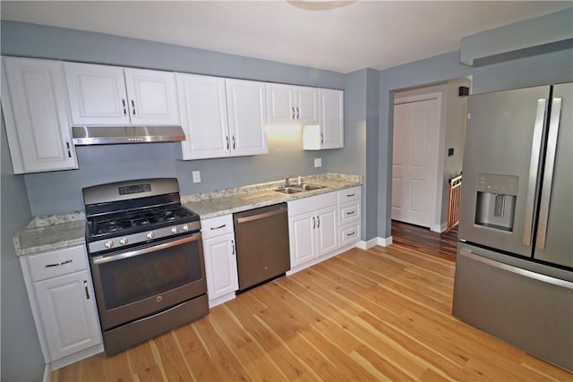 418 Newport Dr, Hempfield Twp Wml, PA 15601 - kitchen with stainless steel appliances, under cabinet range hood, a sink, light wood-style flooring, and white cabinets