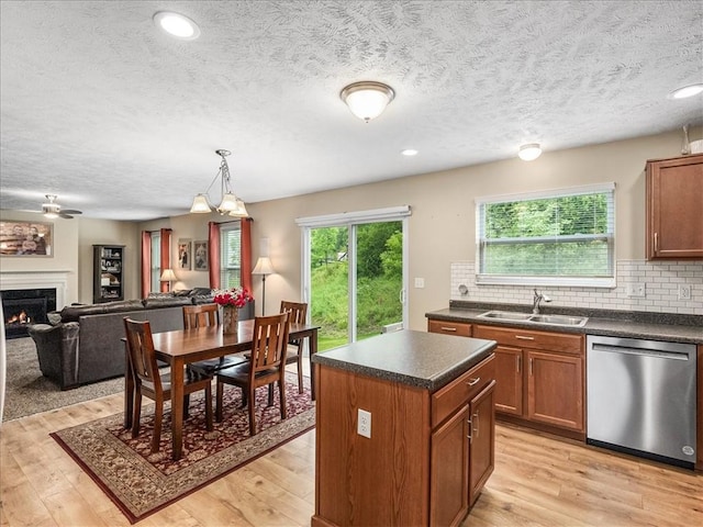 8045 Maureen Dr, Cranberry Twp, PA 16066 - kitchen featuring stainless steel dishwasher, a sink, a warm lit fireplace, dark countertops, and brown cabinets