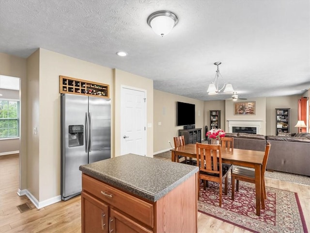 8045 Maureen Dr, Cranberry Twp, PA 16066 - kitchen featuring stainless steel refrigerator with ice dispenser, baseboards, light wood-style floors, a fireplace, and dark countertops