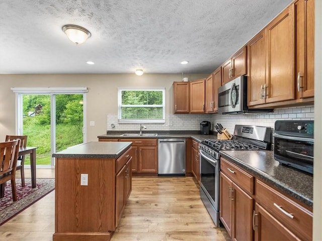 8045 Maureen Dr, Cranberry Twp, PA 16066 - kitchen with stainless steel appliances, a sink, a kitchen island, dark countertops, and light wood-type flooring