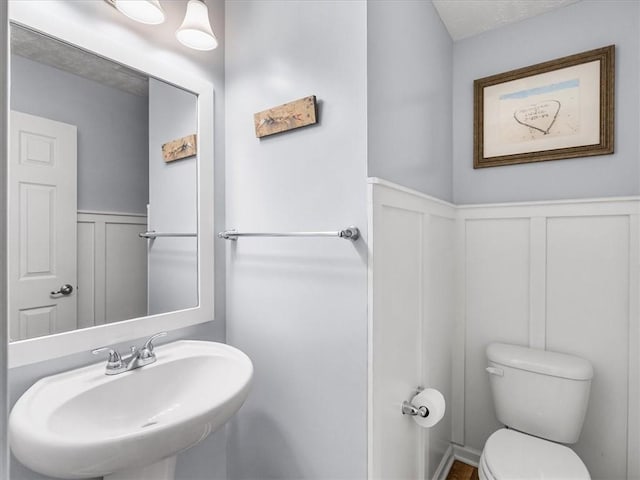 8045 Maureen Dr, Cranberry Twp, PA 16066 - bathroom featuring a decorative wall, a sink, toilet, and a wainscoted wall
