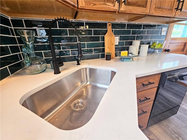 116 Bellwood Rd, West Mifflin, PA 15122 - kitchen view of backsplash, brown cabinetry, black dishwasher, wood finished floors, and light countertops