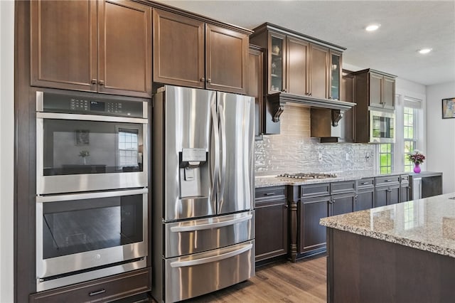 5023 Kensington Dr, Cecil, PA 15317 - kitchen featuring stainless steel appliances, light stone counters, backsplash, dark wood-style floors, and glass insert cabinets