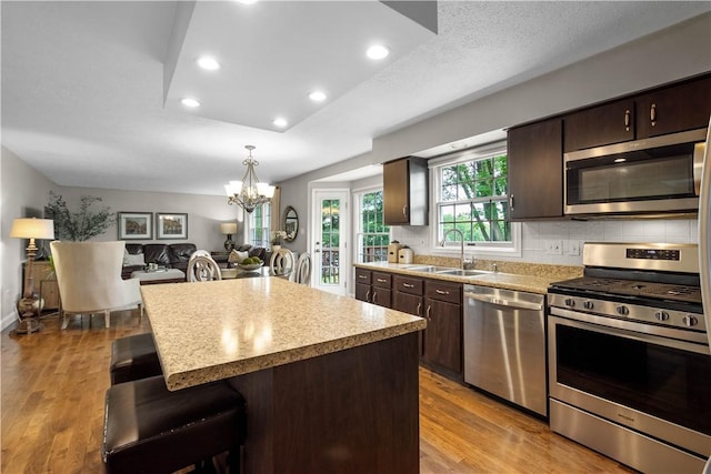 401 Pebble Creek Dr, Cranberry Twp, PA 16066 - kitchen featuring stainless steel appliances, a sink, dark brown cabinetry, a breakfast bar area, and wood finished floors