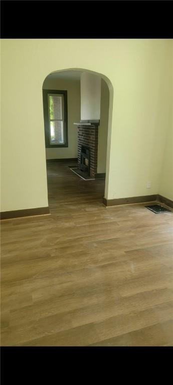 2722 Bethesda St, Carrick, PA 15227 - unfurnished living room featuring wood finished floors, arched walkways, and a fireplace with raised hearth
