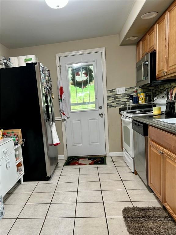 5936 Leprechaun Dr, Bethel Park, PA 15102 - kitchen featuring appliances with stainless steel finishes, light tile patterned floors, backsplash, and dark countertops