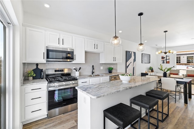 2127 Rose St, Hill District, PA 15219 - kitchen featuring appliances with stainless steel finishes, a sink, backsplash, a kitchen island, and white cabinetry