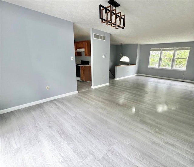 123 Pine Creek Dr, Peters Twp, PA 15367 - unfurnished living room with a chandelier, baseboards, light wood-style flooring, and a textured ceiling