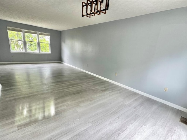 123 Pine Creek Dr, Peters Twp, PA 15367 - spare room featuring baseboards, a chandelier, a textured ceiling, and wood finished floors