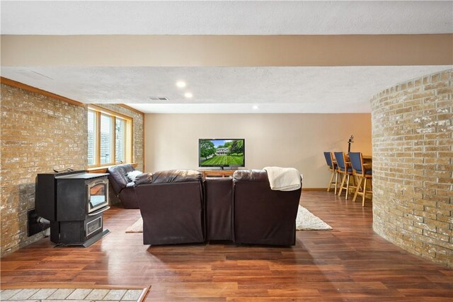 565 Leeper Rd, Green Twp, PA 15043 - living room with wood finished floors, a wood stove, a textured ceiling, brick wall, and baseboards