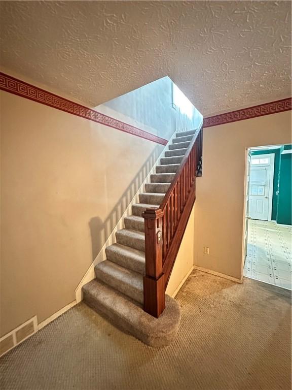 1308 Main St, Aliquippa, PA 15001 - staircase featuring carpet flooring, a textured ceiling, and baseboards