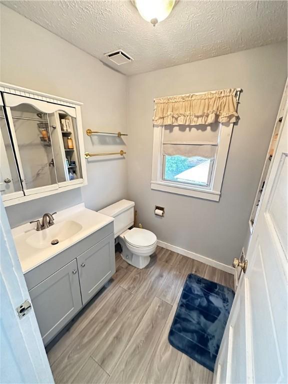 1308 Main St, Aliquippa, PA 15001 - full bath with vanity, toilet, wood finished floors, a textured ceiling, and baseboards