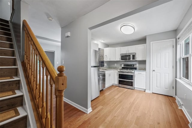 331 Glaser Ave Unit C, Bellevue, PA 15202 - kitchen featuring appliances with stainless steel finishes, baseboards, light wood-type flooring, light stone counters, and white cabinetry