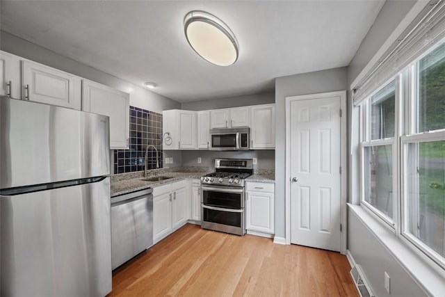 331 Glaser Ave Unit C, Bellevue, PA 15202 - kitchen with appliances with stainless steel finishes, a sink, white cabinets, light stone countertops, and light wood-style floors