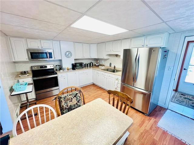 1129 1st St, Redstone Twp, PA 15442 - kitchen with stainless steel appliances, white cabinetry, light wood-style flooring, a drop ceiling, and light countertops