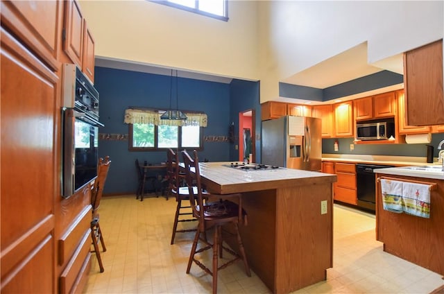 105 Janice Ln, Saxonburg, PA 16056 - kitchen with black appliances, a breakfast bar, a center island, light flooring, and tile counters