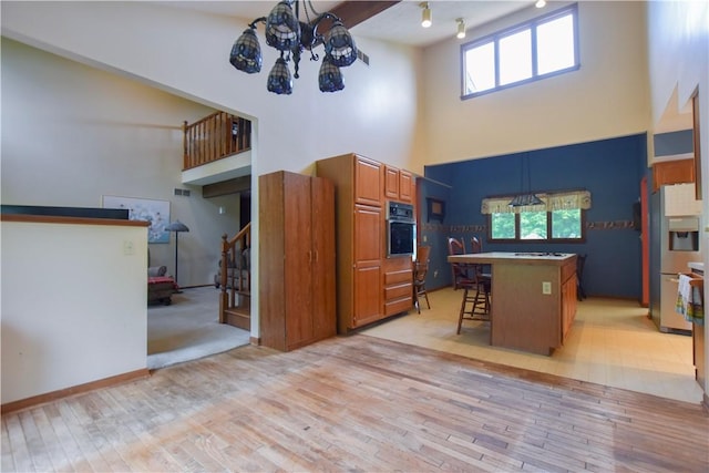 105 Janice Ln, Saxonburg, PA 16056 - kitchen featuring oven, a towering ceiling, brown cabinets, light wood-type flooring, and a kitchen breakfast bar