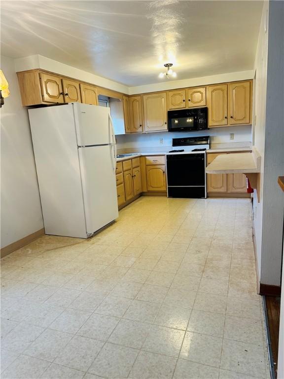 1026 Jefferson Ave, Jeannette, PA 15644 - kitchen with electric stove, black microwave, freestanding refrigerator, light countertops, and baseboards
