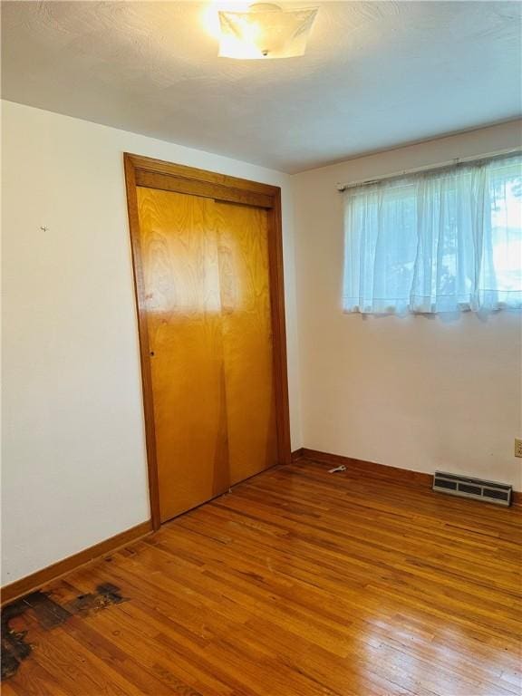 1026 Jefferson Ave, Jeannette, PA 15644 - unfurnished bedroom featuring a closet, hardwood / wood-style flooring, multiple windows, and baseboards