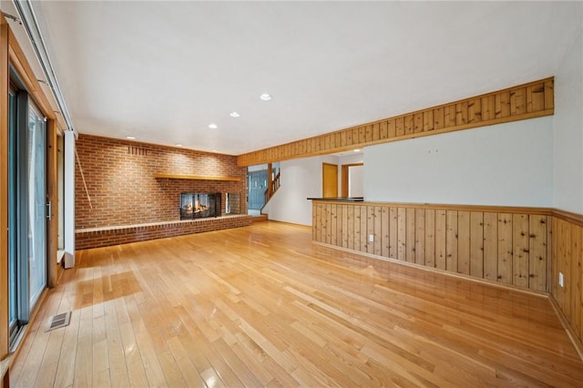 490 Hillside Ave, Monroeville, PA 15146 - unfurnished living room with light wood-style flooring, a fireplace, wainscoting, recessed lighting, and brick wall