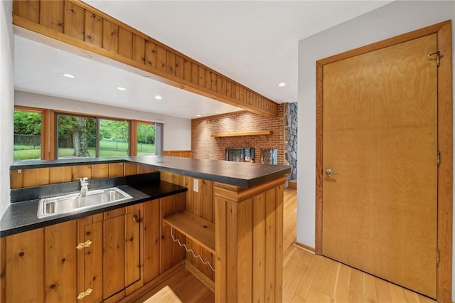 490 Hillside Ave, Monroeville, PA 15146 - kitchen with a sink, dark countertops, light wood finished floors, a fireplace, and brown cabinetry